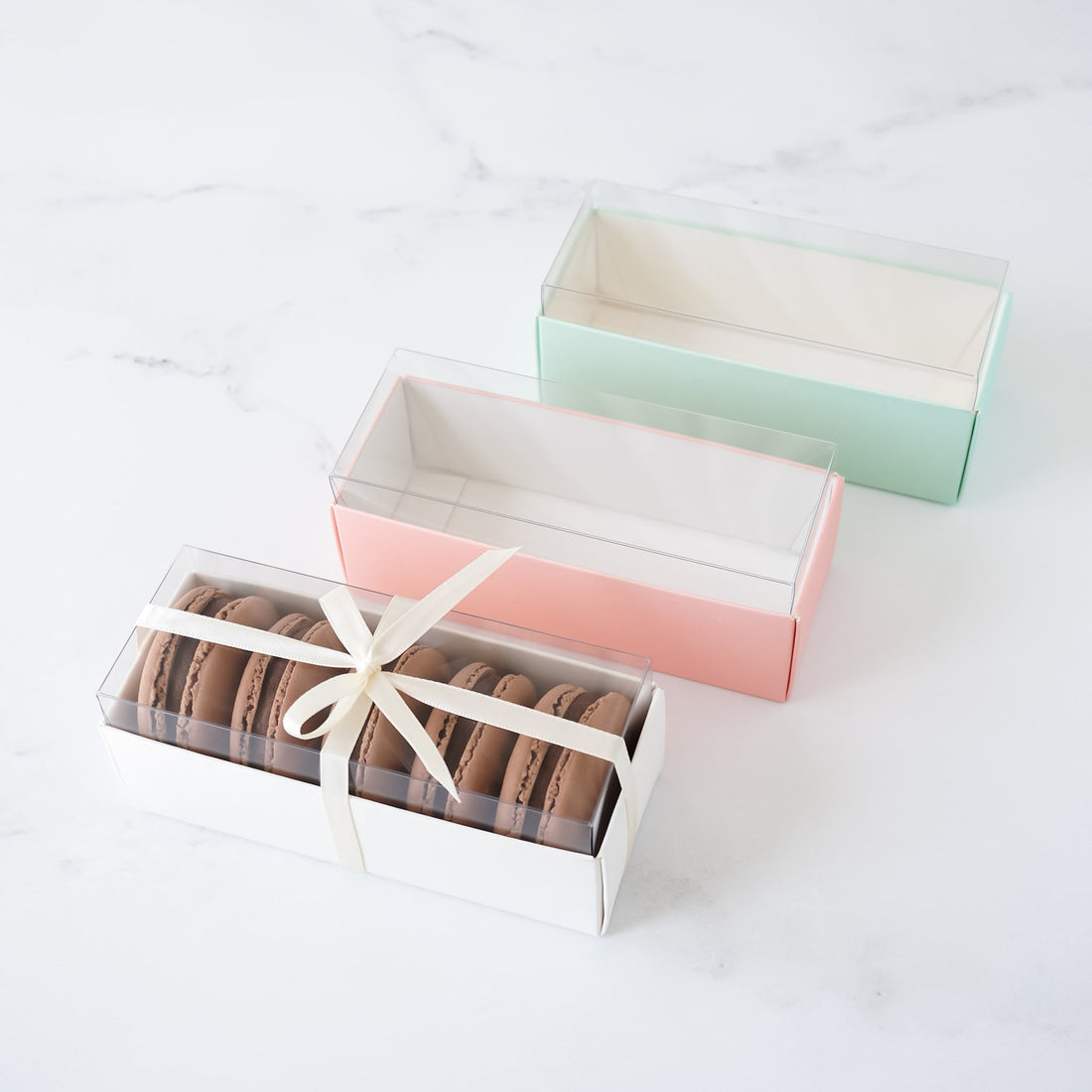 mini macaron boxes with clear lids in white, pink, and mint