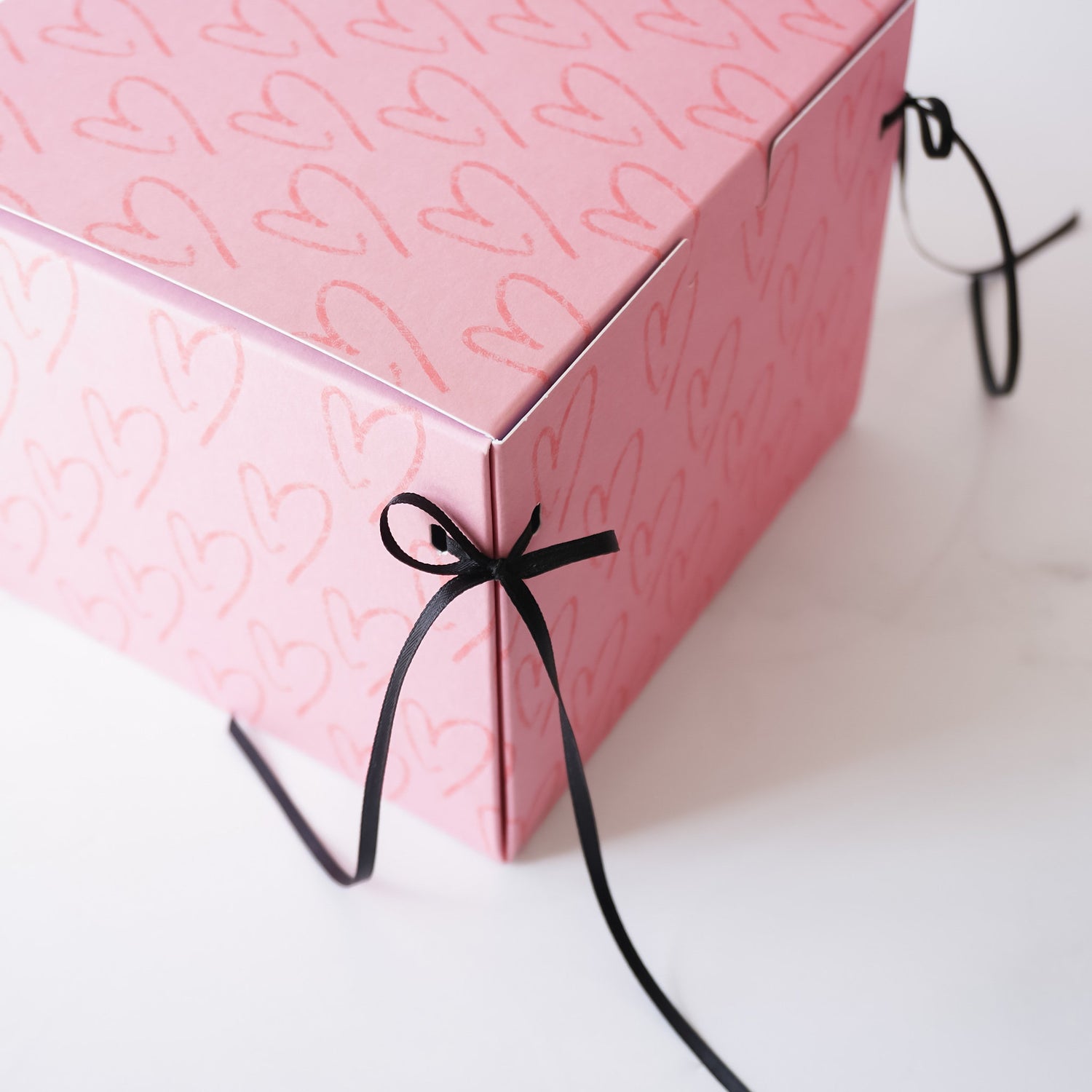 pink bakery box with black satin ribbon