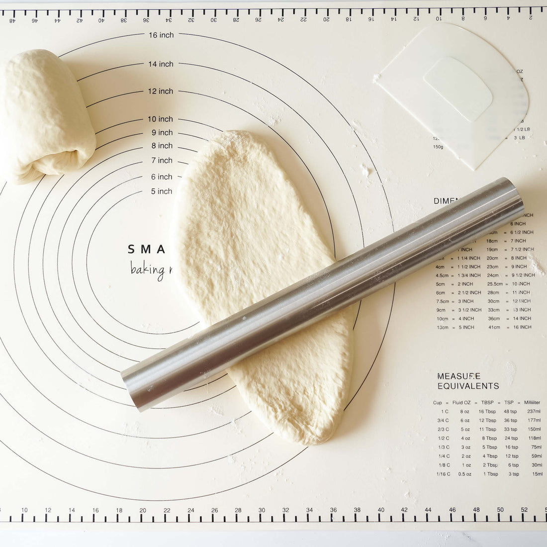 rolling pin and dough scraper on a baking mat